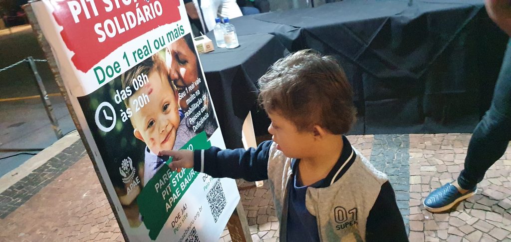 Lucas, criança que estampa a campanha, vendo sua imagem no cavalete usado durante o 1º Pit Stop Solidário